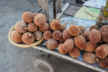 Light brown baobab tree fruits displayed at street market, heap placed on simple wooden cart,...