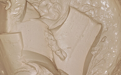 Wet mortar cement paste mixed with masonry trowel in bucket, closeup detail from above