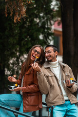A photo of a modern man and woman enjoying the city and eating delicious fresh poffertjes. High quality photo