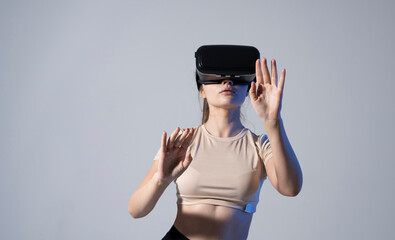 Young beautiful brunette woman wearing a VR headset and experiencing a virtual reality simulation, metaverse and cyberspace concept. Future technology concept.