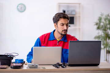 Young male repairman repairing computer