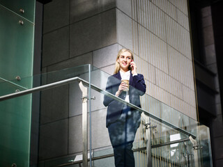 young caucasian businesswoman making a call using mobile phone inside modern office building