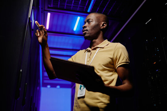 Low angle view at African American network engineer holding tablet in server room of data center