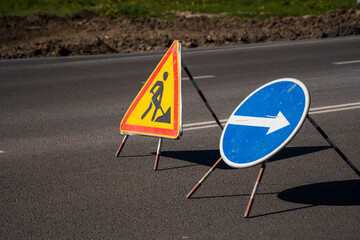 Road signs indicating the repair of asphalt and the direction to bypass the dangerous section....