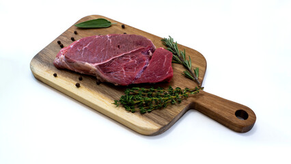 fresh raw beef steak on wooden cutting board with spices and rosemary isolated on white background. High-quality photo