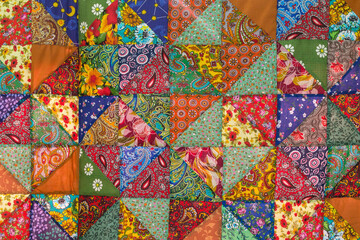 Quilt, colorful fabric texture with flowers and geometric patterns. Floral red orange green blue...