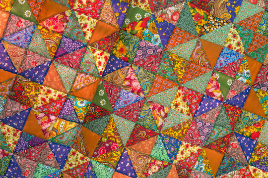 Quilt, colorful fabric texture with flowers and geometric patterns. Floral red orange green blue yellow textile background © Viktor Iden
