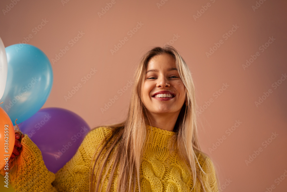 Wall mural studio portrait of a happy young blonde woman with balloons over pink background. - Wall murals