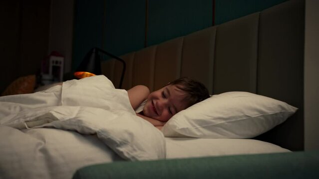Close-up face of a sleeping child baby on its side. Tracking shot sleeping baby at midnight. Sleeping baby in bed. Six-year-old boy sleeps sweetly in his crib and smiles in his sleep.