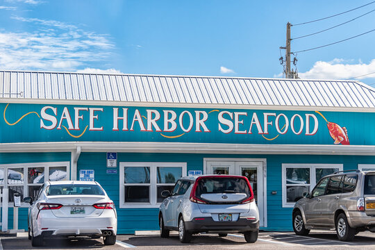 Crescent Beach, USA - October 19, 2021: Beach near Marineland, Florida with sign for Safe Harbor Seafood restaurant with vintage blue architecture and parked cars by entrance