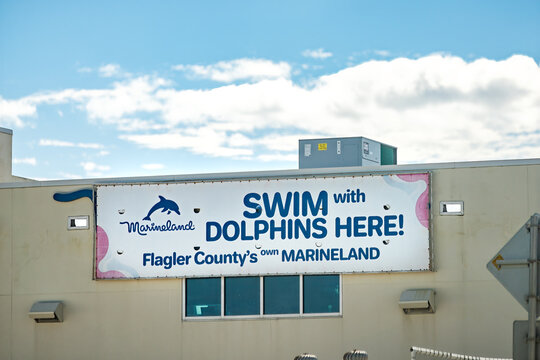 Marineland, USA - October 19, 2021: Swim With Dolphins Here sign in north Florida palm coast on building in Flagler County for Marineland Dolphin Adventure