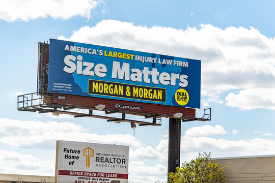 Orlando, USA - October 19, 2021: Roadside billboard for civil injury law firm Morgan & Morgan advertising professional services with board for Orlando Florida regional realtor by cityscape skyline