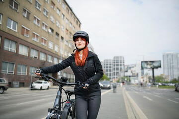 Portrait of businesswoman commuter on the way to work with bike looking at camera, sustainable...
