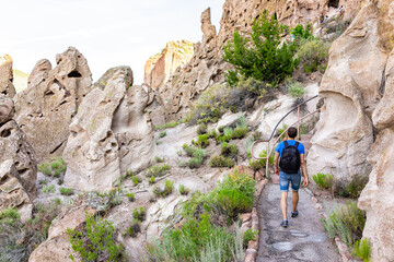 Man hiking walking on Main Loop trail footpath in Bandelier National Monument in New Mexico, USA during summer with cliff cave dwellings used by native people