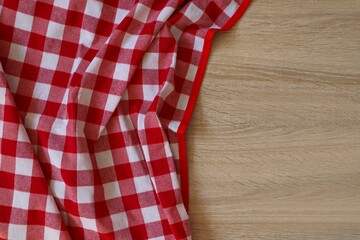 Fototapeta premium Checkered picnic cloth on wooden table, top view. Space for text