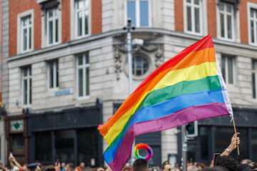 Diverse people are walking on a gay pride parade on the city streets with flags. High quality photo