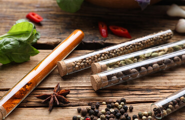 Fragrant spices in glass test tubes on wooden table, closeup