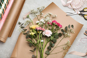 Beautiful flowers and wrapping papers on grey table, flat lay. Arranging bouquet