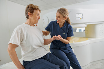 Radiologist help to patient sit after procedure of MRI or CT Scan . High Tech medical equipment