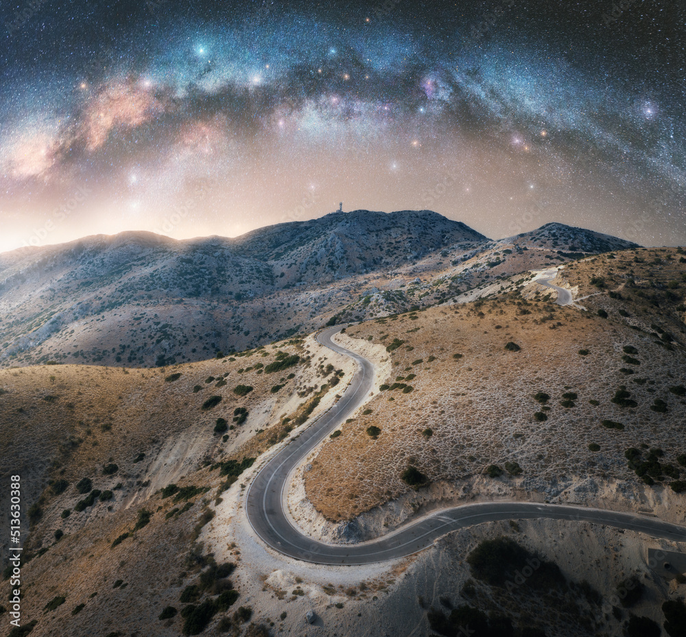 Wall mural milky way arch and winding mountain road at night. sky with arched milky way and bright stars in sum