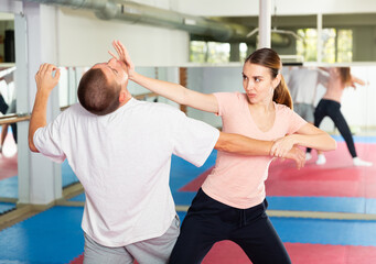 Fototapeta na wymiar Young woman paired up with male partner in self defense training, practicing basic palm strike..