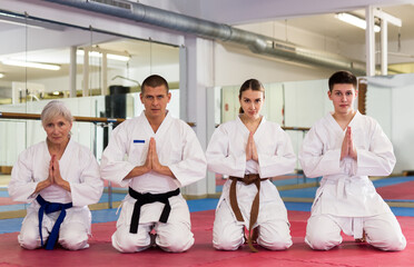 Group of athletes in kimono sit on a tatami before preparing for sparring