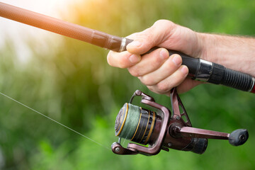Summer fishing on the lake, a man's hand holds a fishing rod, close-up