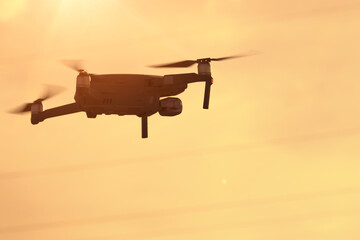 The quadcopter flies right at sunset, a modern quadcopter soars in the air