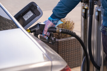 Diesel.Fuel price in Europe. Refueling the car.Refueling pistol in the hands of a man in a blue glove.Car at a gas station. Silver car, refueling pistols and gloves