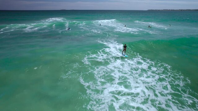 hombre joven surfeando una ola del mar con seguimiento de dron 
