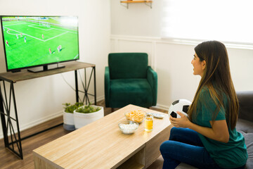Rear view of a smiling sports fan enjoying a soccer game on tv