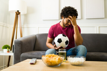 Sad sports fan losing the game with his favorite soccer team