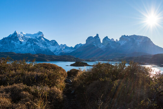 cuernos del Paine , octava maravilla del mundo, monta&ntilde;as, con cielo despejado azul con sol radiante, estepa patag&oacute;nica con lago azul con islas  