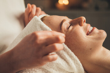Close-up portrait of a woman getting face massage in spa salon. Doctor hands. Pretty female...