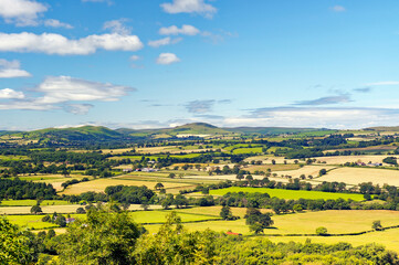 Southwest from Wenlock Edge near Easthope over summer farmland of Ape Dale to Caer Cardoc and The...