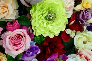 Bright colorful fake flowers and leaves decorating surface. Close up