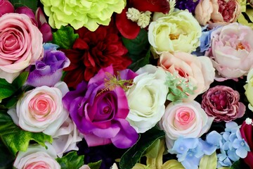 Bright colorful fake flowers and leaves decorating surface. Close up