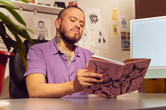 Latino Gay Con Tatuajes Sentado En Un Escritorio Leyendo Agenda