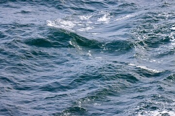 Waves far in open Baltic sea. Deep blue water, white foam on top of waves. Photo taken from ship