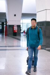 young man smiling walking with a suitcase