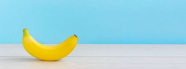 A banana on the table.  light blue background.  テーブルの上のバナナ。　水色背景 - obrazy, fototapety, plakaty