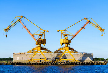 Two large industrial cranes on tracks attached to a waterfront warehouse in Norfolk Virginia