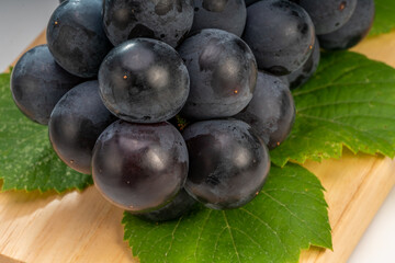 Organic black grapes on wooden plate, Fresh Kyoho Grape on black background. 