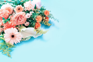 Bouquet of gerbera, roses and carnations on blue background copy space.