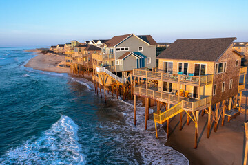 Aerial view of homes right on the shoreline in the ocean during high tide in Buxton North Carolina Outer Banks - obrazy, fototapety, plakaty