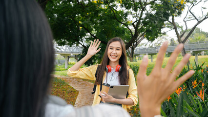 Two beautiful young Asian students are hugging each other lovingly in the park. Further education, scholarship, opportunity.University graduate ,say hi hello ,good bye,happy students positive concept. © Chalermphon