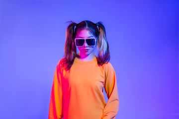 Obraz na płótnie Canvas Young asian girl in yellow sweatshirt wearing sunglasses posing on blue screen background. 