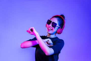 Young asian girl in black t-shirt wearing sunglasses and red headphones listen to music and dancing...
