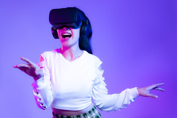 Metaverse concept, young asian girl in white fashion sweatshirt wearing vr headset playing touching online game purple background.
