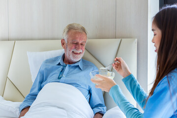 Elderly care feeding an elderly woman at retirement house. Caregiver nurse take care a Senior...